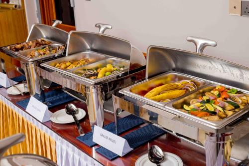 ein Buffet mit Tabletts verschiedener Arten von Speisen in der Unterkunft HADJENS HOTEL in Mwanza