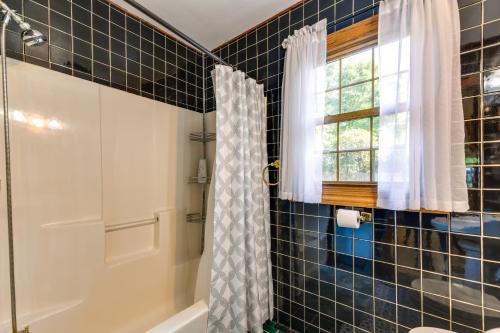 baño con bañera y ducha y ventana en South Burlington Home with Seasonal Pool! en South Burlington