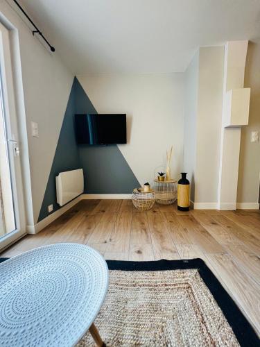 un salon avec une table et une télévision au mur dans l'établissement Scorfel Lodge, Maison bleue, Terrasse, 1km mer, à Trégastel