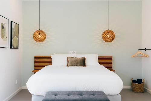 a bedroom with a white bed and two pendant lights at Pietermaai Oasis in Willemstad