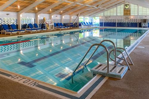 a large swimming pool with blue chairs in it at Sand, Shells & Sunsets in Brewster