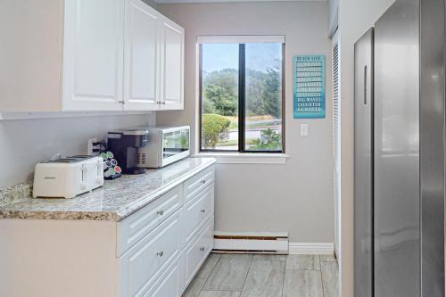 a kitchen with white cabinets and a window at Sand, Shells & Sunsets in Brewster