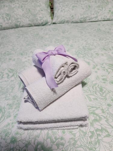 un asciugamano con un fiocco viola sopra al letto di Relax La Torricella a Fonte Nuova