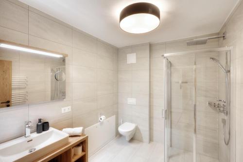 a bathroom with a shower and a toilet and a sink at Alpenstolz Damüls Haus 2 - Stilvoll urlauben in den Bergen in Damuls