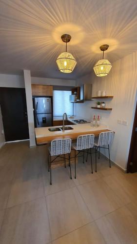 a kitchen with a table and chairs and two lights at Bonito Departamento cerca de las Playas del Puerto de Mazatlán. in Mazatlán