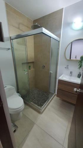 a bathroom with a shower and a toilet and a sink at Bonito Departamento cerca de las Playas del Puerto de Mazatlán. in Mazatlán