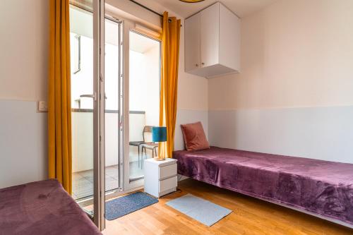 Cette chambre comprend un lit violet et une fenêtre. dans l'établissement Apartament Chmielna Gold, à Cracovie