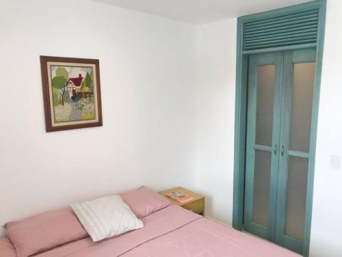 Un dormitorio con una cama rosa y una foto en la pared en Beautiful and cozy apartment en Villeta