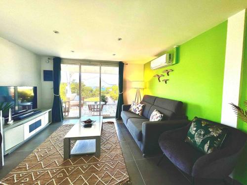 uma sala de estar com um sofá e uma televisão em Duplex Green Paradise , piscine , accès mer 5mn em Le Diamant