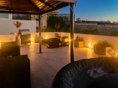 a patio with a couch and a table and lights at Valletta and Grand Harbour Lookout in Kalkara