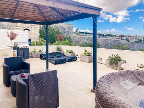 a patio with a bed and chairs and a fireplace at Valletta and Grand Harbour Lookout in Kalkara