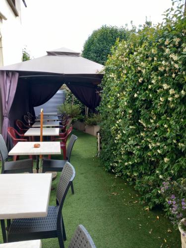 une rangée de tables et de chaises avec un parasol dans l'établissement Hôtel Restaurant O REGAL, à Villeneuve-sur-Lot