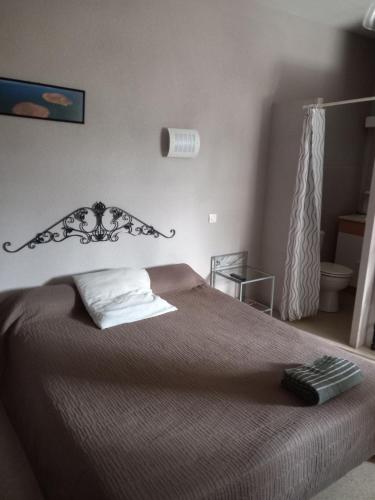 ein Schlafzimmer mit einem Bett mit einer braunen Tagesdecke in der Unterkunft Hôtel Restaurant O REGAL in Villeneuve-sur-Lot