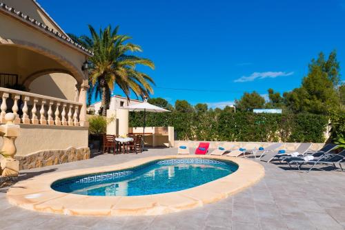 a swimming pool in a patio with chairs and a table at Villa Llobell - Plusholidays in Moraira