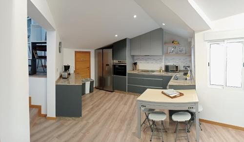 a kitchen with gray cabinets and a table with stools at Mirador Porta da Vila, Noia in Noya