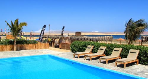 uma piscina com quatro cadeiras e a praia em Bamboo Paracas Resort em Paracas