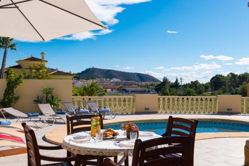 un patio con mesa, sillas y piscina en Villa Llobell - Plusholidays, en Moraira