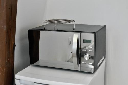 un four micro-ondes installé au-dessus d'une étagère dans l'établissement La Domus Lemaitre 8 - formule éco -parking - WIFI - autoroute, à Bavay