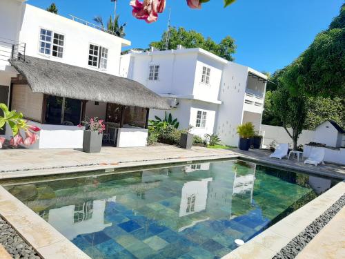a villa with a swimming pool in front of a house at Le Beau Manguier Residence Bed & Breakfast in Pereybere