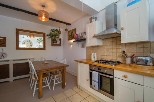 a kitchen with white cabinets and a wooden table at Lobster Cottage in Ventnor