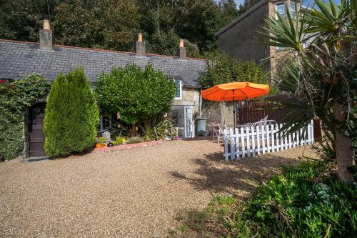 a house with a white fence and an orange umbrella at Lobster Cottage in Ventnor