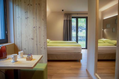 a room with two beds and a table and a mirror at Balibà Ride & Relax in Castione Andevenno