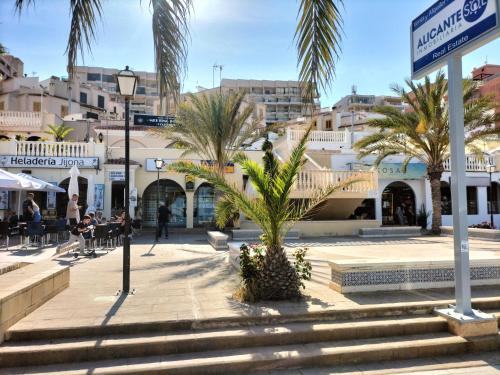 Una calle con palmeras y gente sentada en cafés. en Dune Beach, en Arenales del Sol
