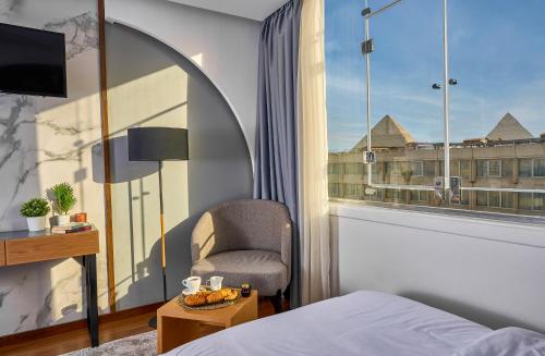 a bedroom with a chair and a window with a view at Peace Inn West Pyramids Cairo in Cairo