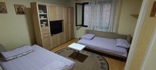 Habitación pequeña con 2 camas y TV. en Apartmani Stojković Kuršumlija en Kuršumlija