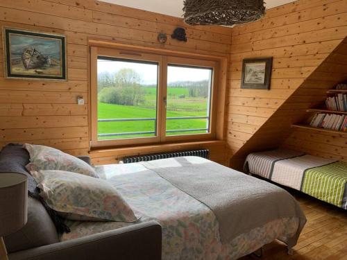 ein Schlafzimmer mit einem Bett und einem Fenster in einer Hütte in der Unterkunft Lumière et verdure, maison de campagne in Miniac-Morvan