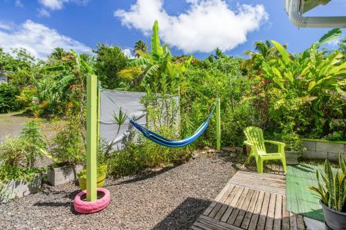 a hammock in a garden with a fence at Ti-colibri ✓Iguana Village in Sainte-Luce