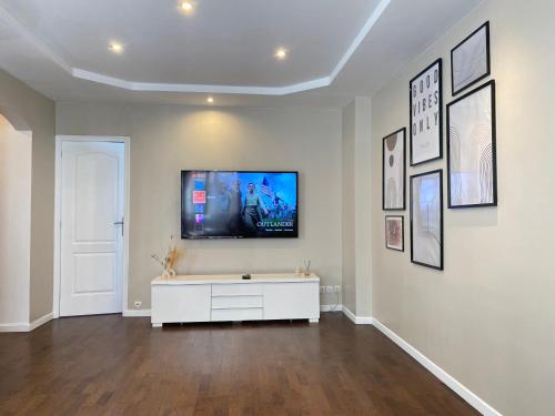 a white living room with a tv on the wall at Bel appartement proche de Paris in Colombes