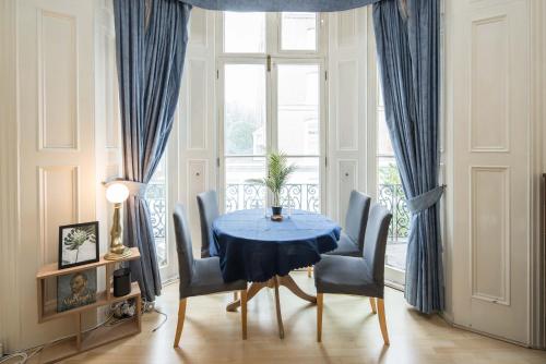 a dining room with a blue table and chairs at Cosy High-ceiling Victorian flat with balcony - 2mins to Hyde Park, Kensington Palace, NottingHill, High Street Kensington,2BR 2Baths in London