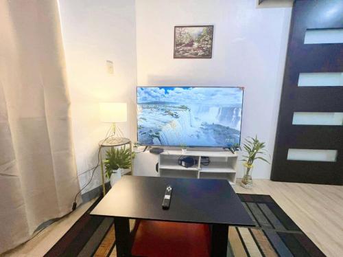 a living room with a table and a large screen tv at One Bedroom Condo with fast wifi at Eastwood Lafayette tower Quezon city in Manila