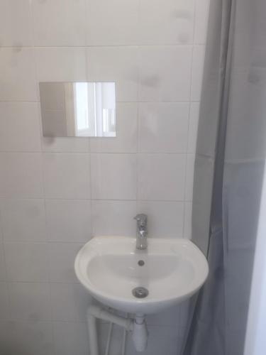 uma casa de banho branca com um lavatório e um espelho em Oasis de détente em Aubervilliers