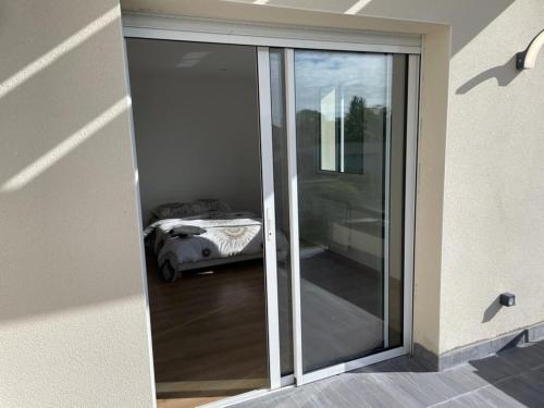 Una puerta corredera de cristal con una cama en una habitación en VILLA LENA en Sainte-Geneviève-des-Bois