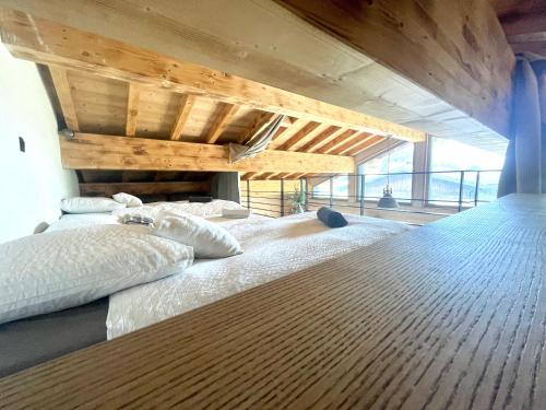 a large bed with white pillows in a room at Chalet le petit Nicolas, jacuzzi, vue Mont Blanc in Chamonix-Mont-Blanc