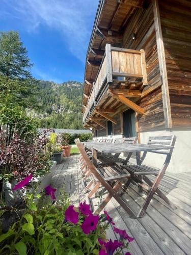 a wooden deck with a picnic table and flowers at Chalet le petit Nicolas, jacuzzi, vue Mont Blanc in Chamonix-Mont-Blanc
