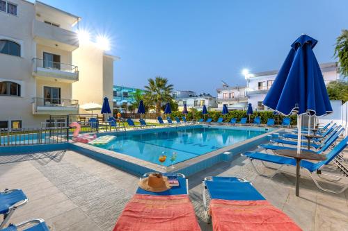 a swimming pool with chairs and umbrellas next to a building at Anixis Hotel & Apartments in Ialyssos
