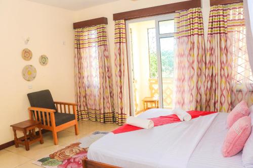 a bedroom with a bed and a window and a chair at Serebian Suites in Mombasa