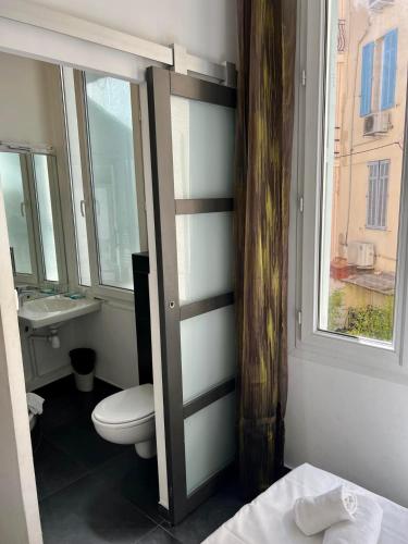 a bathroom with a toilet and a sink and a window at Chanteclair in Cannes