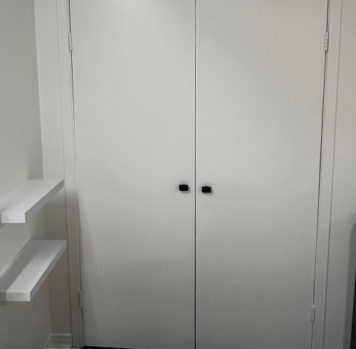 a white cabinet with two doors in a room at Bright, Private, Peaceful Suite with Retail Conveniences Steps Away in Toronto