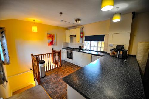 a kitchen with yellow walls and a black counter top at The Coachman Hartford in Hartford