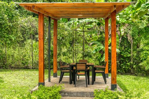 a wooden gazebo with a table and chairs under it at Casa Eureka in Herradura