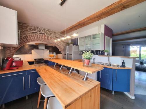 une cuisine avec des placards bleus et un comptoir en bois dans l'établissement Gîte authentique avec terrasse et tout confort, entre Monts du Lyonnais et bassin Stéphanois - FR-1-496-299, à Tartaras