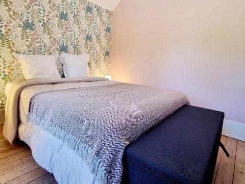 a bedroom with a bed with a blue ottoman next to it at Maison indépendante en lisière de bois avec jardin, vélos, baby-foot et cheminée près de Paris. - FR-1-532-20 in Fontenelle