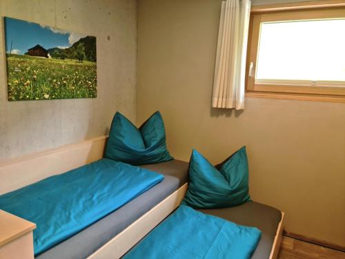 um quarto com duas almofadas azuis num sofá em Chesa Bunita Trais em Gaschurn