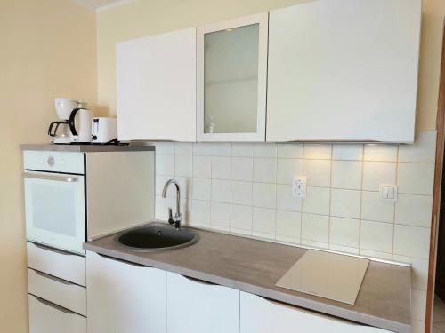 a kitchen with white cabinets and a sink at Casa Panorama Studio in Rabac