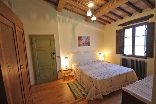 Schlafzimmer mit einem Bett, einem Fenster und einer Tür in der Unterkunft Casetta del Pozzo in Seggiano