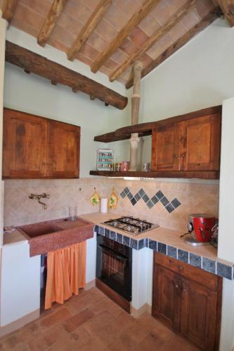 a kitchen with wooden cabinets and a stove top oven at Casetta del Pozzo in Seggiano